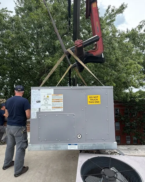 A new rooftop heating and cooling unit for a business, lifted into place by crane